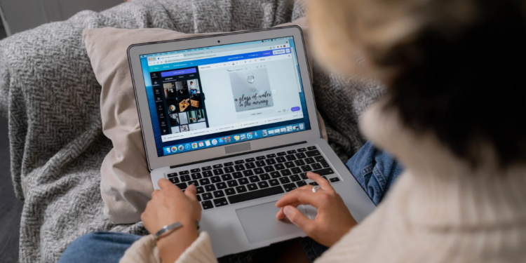 An assistant is sitting with a MacBook Air on her lap and she has Canva on the screen. She is working on a design. Elevate Your Document Game: How Canva Docs Empower Executive Assistants