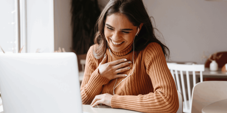 An assistant sitting at a computer on a video call looking happy and supported