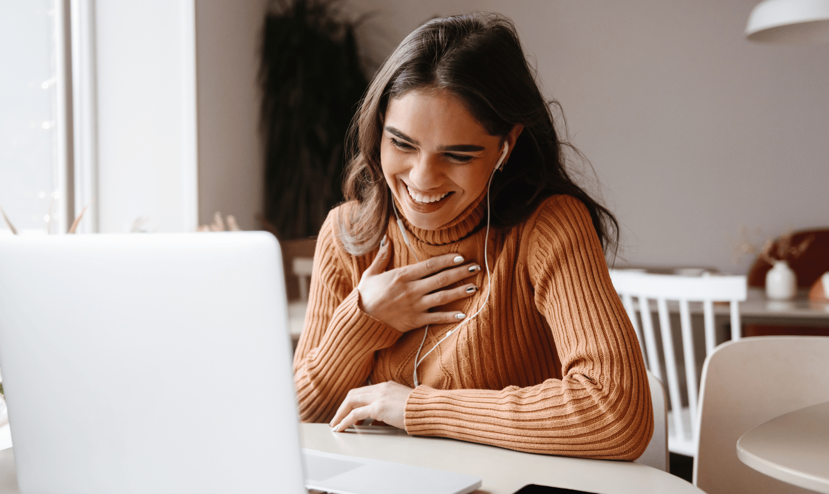 An assistant sitting at a computer on a video call looking happy and supported